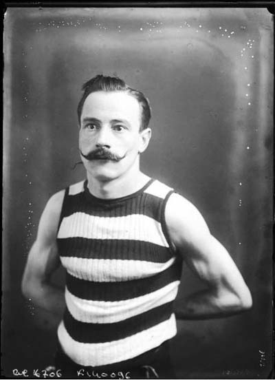 Photograph of a man wearing a French striped tank top and a handlebar moustache.