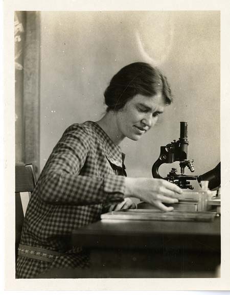 Black and white photograph of woman with microscope