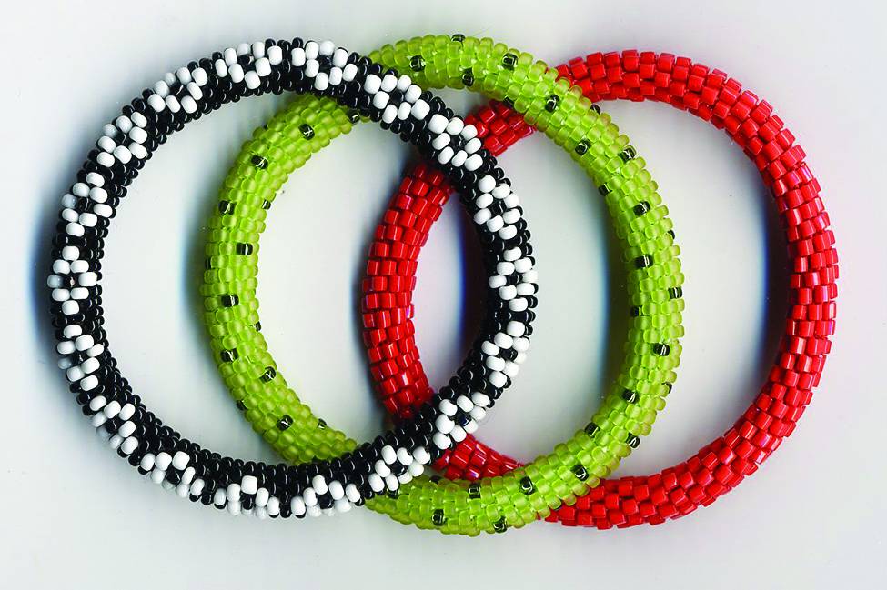 Three beaded bracelets, one black with small white rings, one green with black dots, and one red.