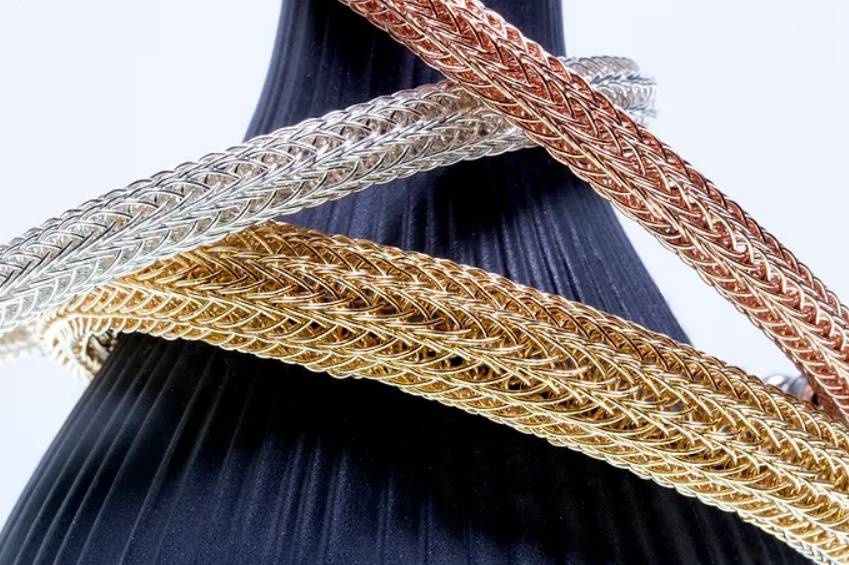 Photo of intertwining silver, gold, and amber colored bracelets.