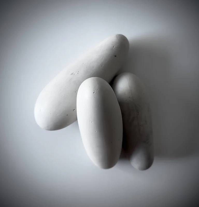 Sculptural work featuring three off-white orbs, leaning on and overlapping one another.