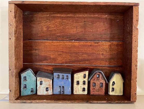 A line of small ceramic houses sitting within a wooden box.