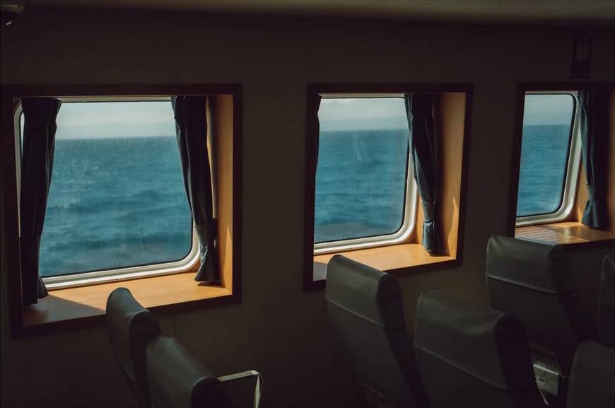 A photograph from a passenger seat on a boat, looking through three windows looking out onto the Atlantic Ocean.