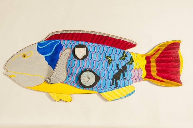 Richly colored sculptural figure of a fish adorned with bright colors plus a a pail, butterflies, and a falling girl in silhouette.
