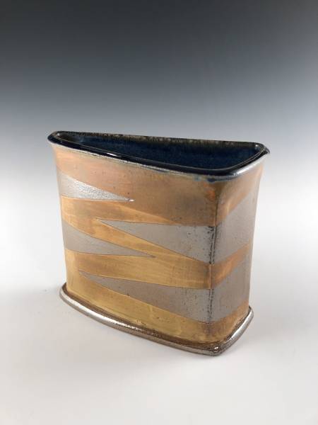 A photograph of a triangular ceramic vessel with brown and gray coloring.