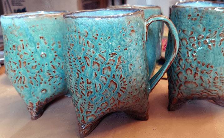 Four handmade blue and brown ceramic mugs on a table.