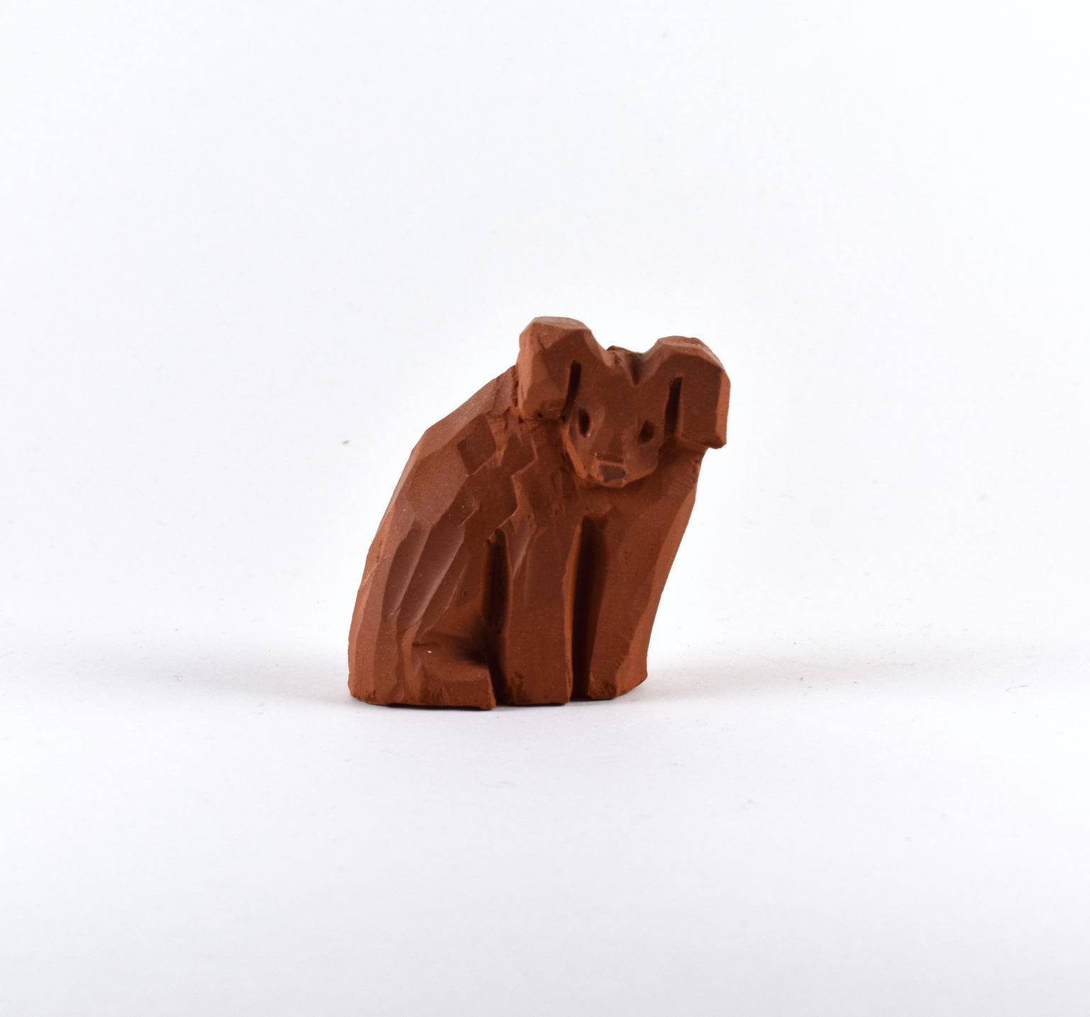 Photograph of a brown clay dog, with an inquisitive aspect, set against a white background.