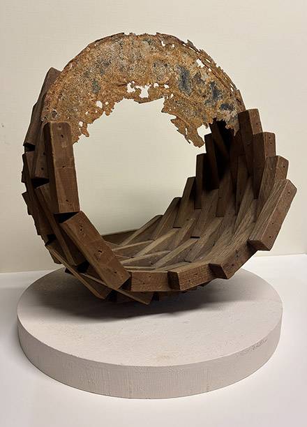 An abstract sculpture featuring a spiral shape constructed of wood blocks and rusted metal.