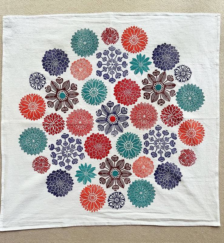 Photograph of a white cloth decorated with hand-stamped floral iconography.