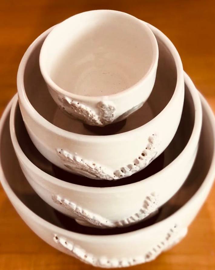 A photograph of four stacked and cradled handmade ceramic bowls.