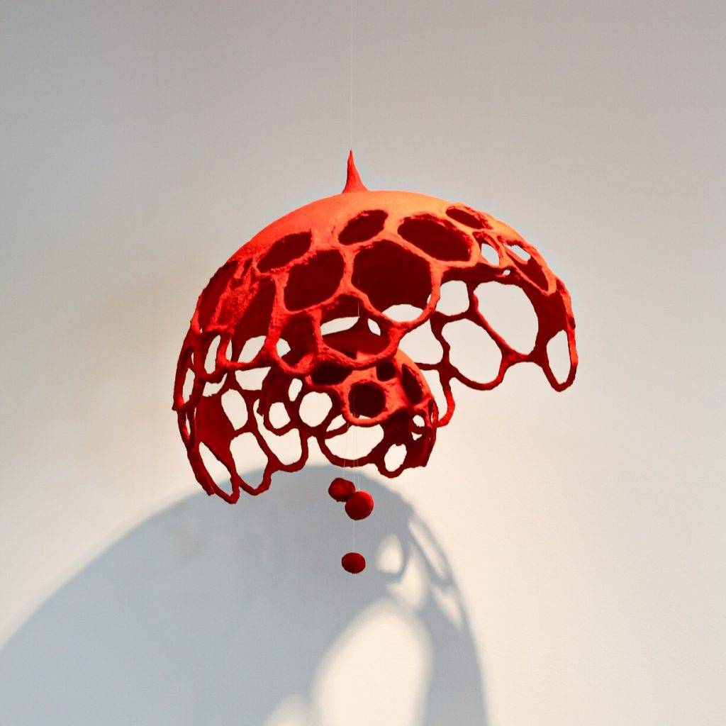 An abstract sculpture resembling a red umbrella.